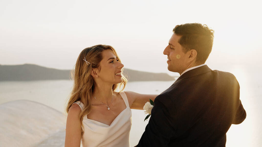Paige and Victor at Andromeda Villas Santorini with the Aegean Sea and volcanic caldera in the background