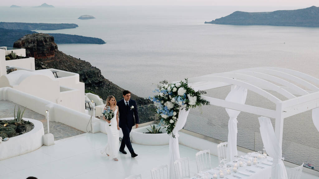 Paige and Victor at Andromeda Villas Santorini with the Aegean Sea and volcanic caldera in the background